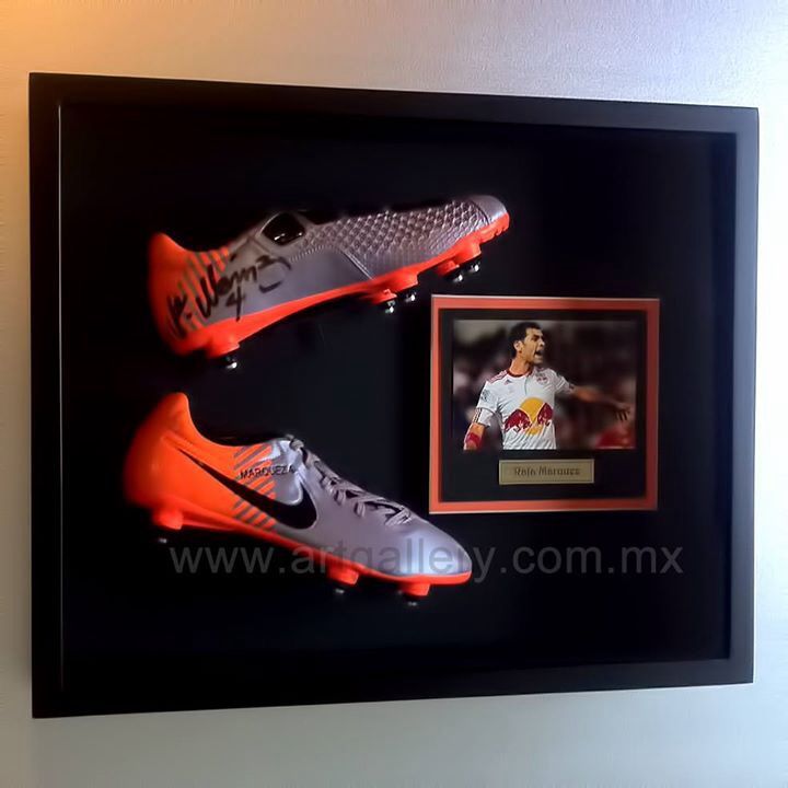 Framed soccer cleats with autograph and player photo display on a wall, highlighting sports memorabilia.