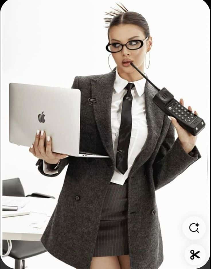_ 11 Businesswoman in glasses multitasks with laptop and vintage cellphone, dressed in formal attire. | Sky Rye Design Businesswoman in glasses multitasks with laptop and vintage cellphone, dressed in formal attire.