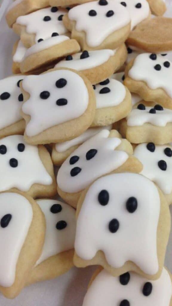 _ 11 Ghost-shaped sugar cookies with white icing and black eyes, perfect for Halloween treats. | Sky Rye Design Ghost-shaped sugar cookies with white icing and black eyes, perfect for Halloween treats.