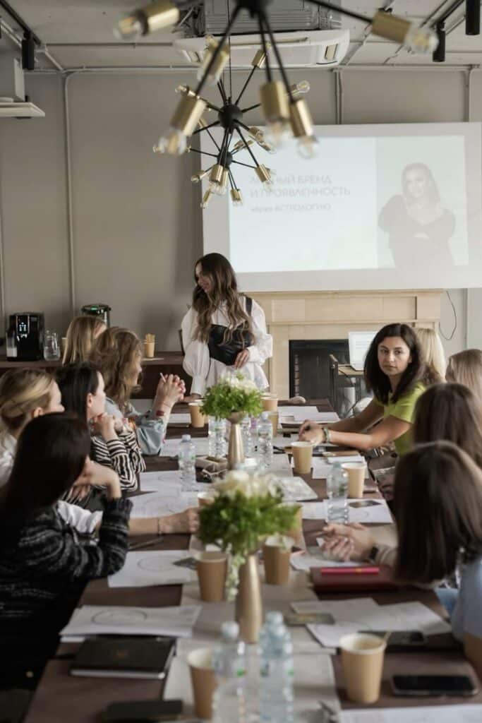 Women attending a workshop with a presentation in a modern conference room, discussing brand identity through astrology.