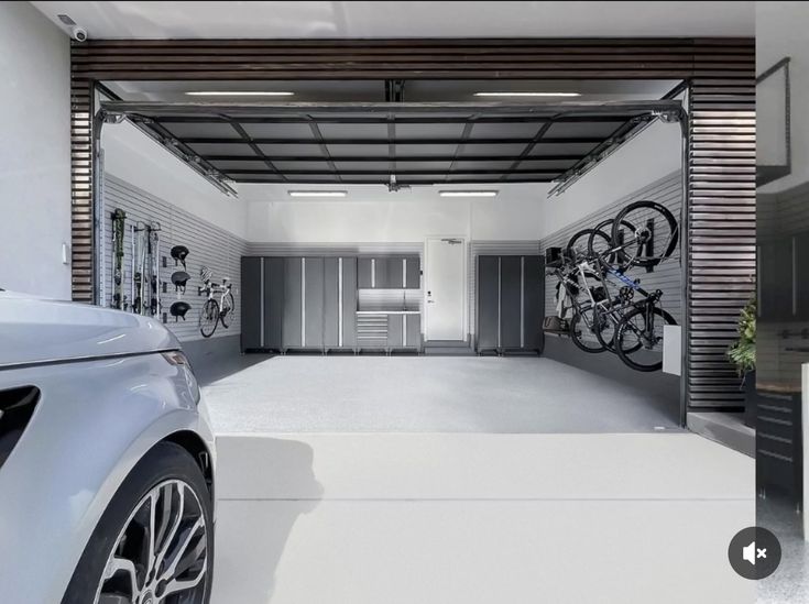 Modern garage with sleek storage cabinets, wall-mounted bikes, and a parked car in foreground.