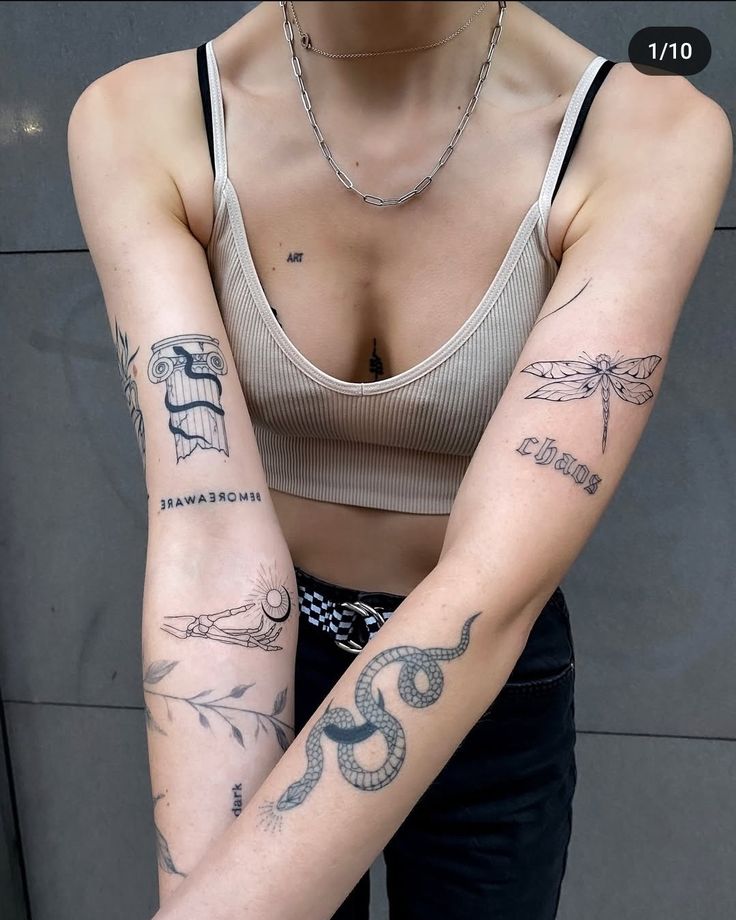 Person with various artistic tattoos on arms, including a snake and dragonfly design, wearing a cropped top.