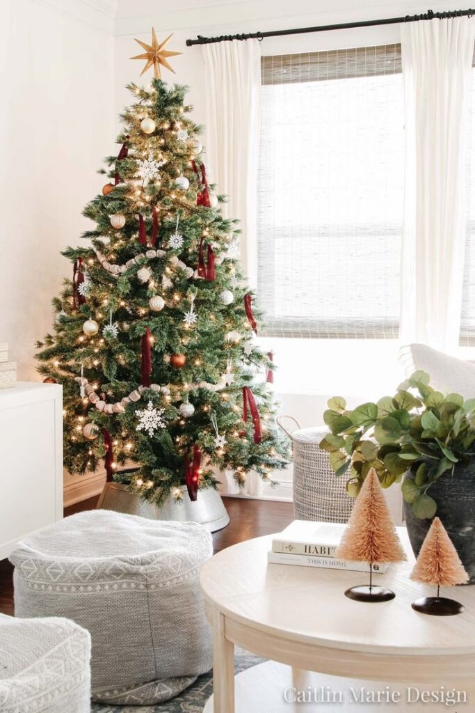 Cozy living room with decorated Christmas tree, white curtains, and festive accents for a warm holiday atmosphere.