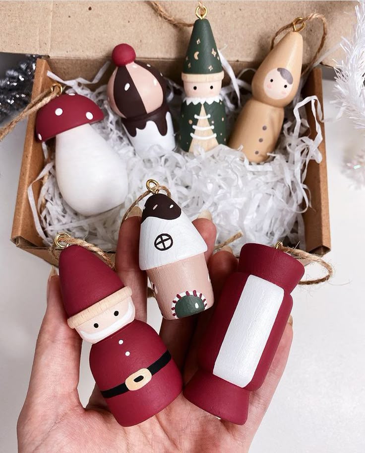 _ 13 Hand holding colorful, handmade Christmas ornaments in a gift box, including Santa and holiday-themed designs. | Sky Rye Design Hand holding colorful, handmade Christmas ornaments in a gift box, including Santa and holiday-themed designs.