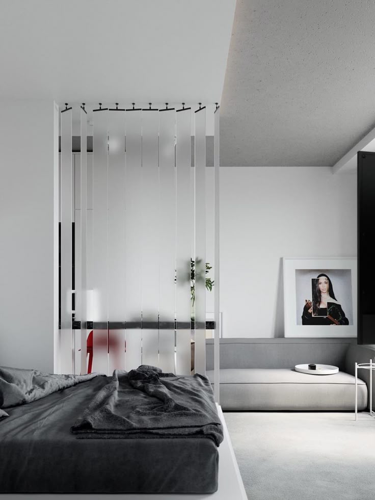 Modern minimalist bedroom with gray bed, white decor, and stylish divider. Cozy and chic interior design.