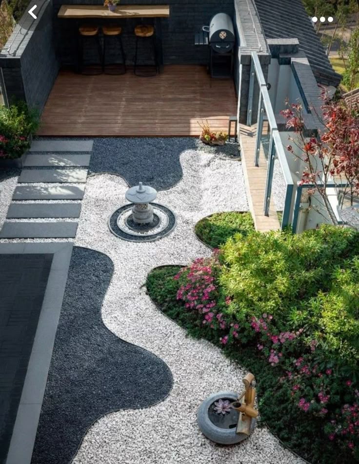 Zen garden with gravel, stepping stones, and greenery alongside a wooden deck and outdoor seating.