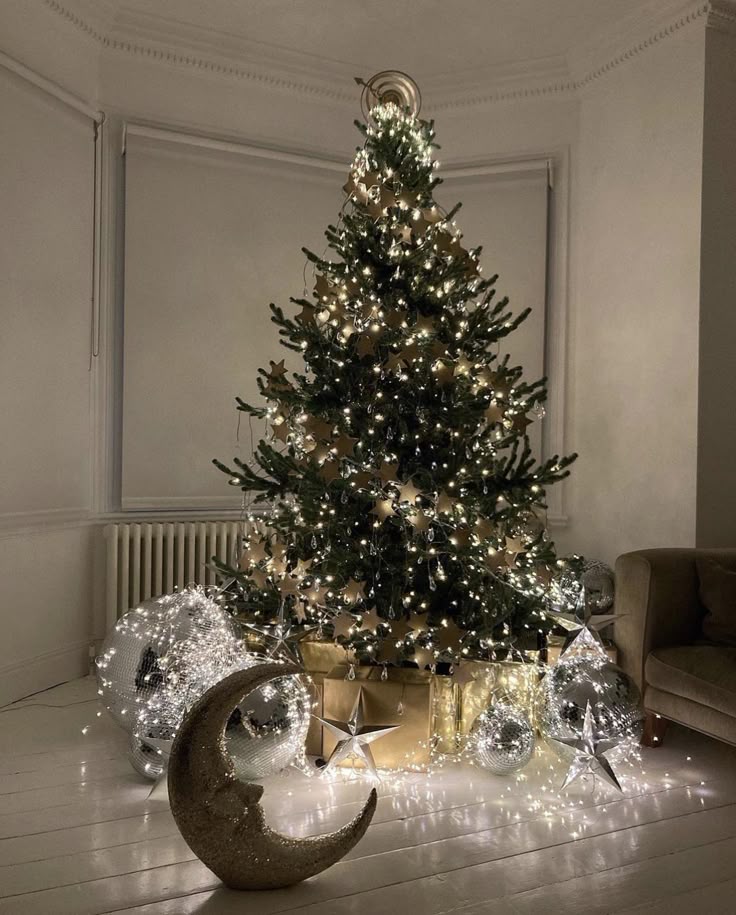 Elegant Christmas tree adorned with white lights, gold stars, silver disco balls, and a crescent moon ornament.