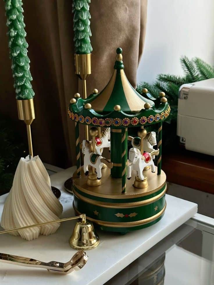 _ 15 Musical carousel with horses and festive decorations on a table, surrounded by candles and a bell. | Sky Rye Design Musical carousel with horses and festive decorations on a table, surrounded by candles and a bell.