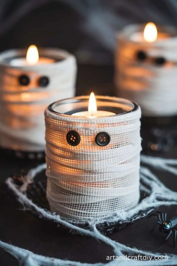 Spooky DIY mummy candles with button eyes, perfect for Halloween decor and atmospheric lighting.