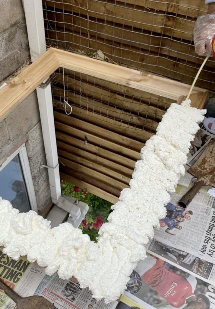 Wooden frame being sealed with expanding foam insulation for weatherproofing.