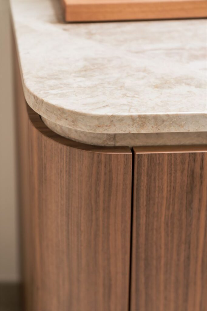 Elegant wooden cabinet with a smooth marble countertop, showcasing modern kitchen design.