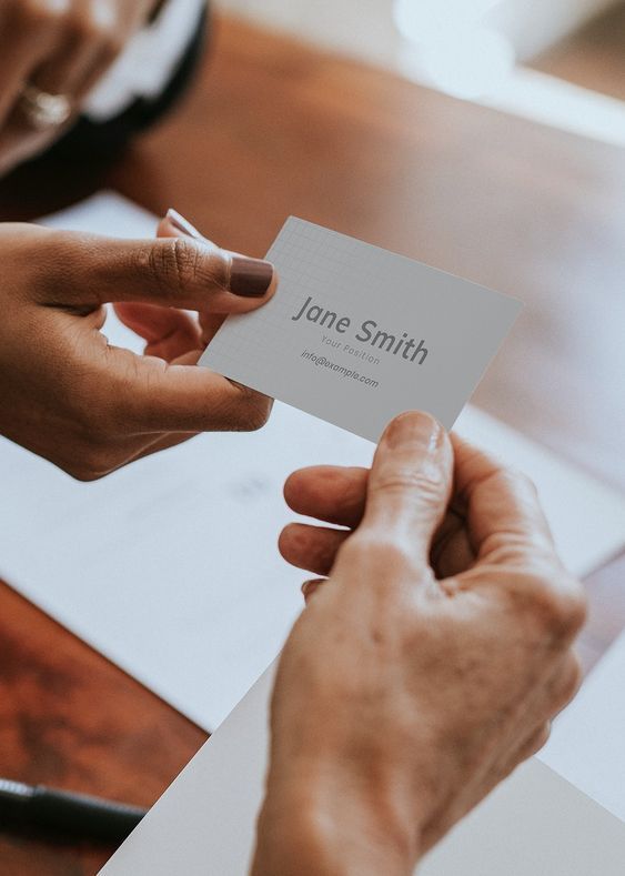 Person handing over a business card in a professional setting.