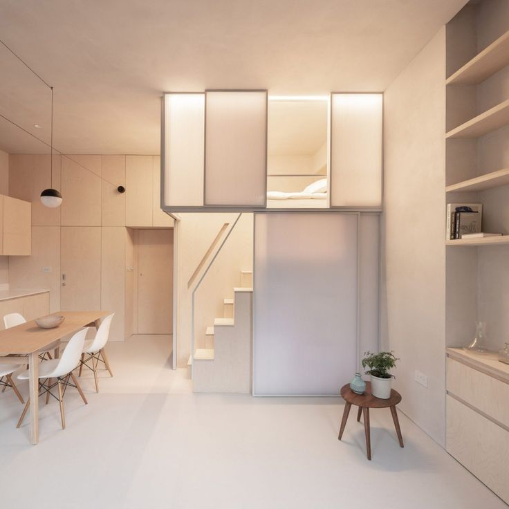 Minimalist studio apartment with loft bed, wooden dining setup, and modern decor.