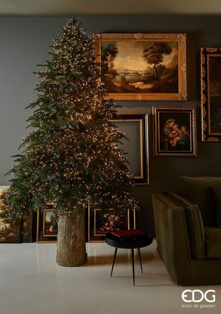 Elegant Christmas tree with lights in a cozy room adorned with classic framed paintings.