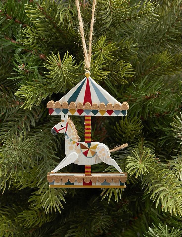 _ 16 Carousel horse ornament hanging on a green Christmas tree branch. | Sky Rye Design Carousel horse ornament hanging on a green Christmas tree branch.