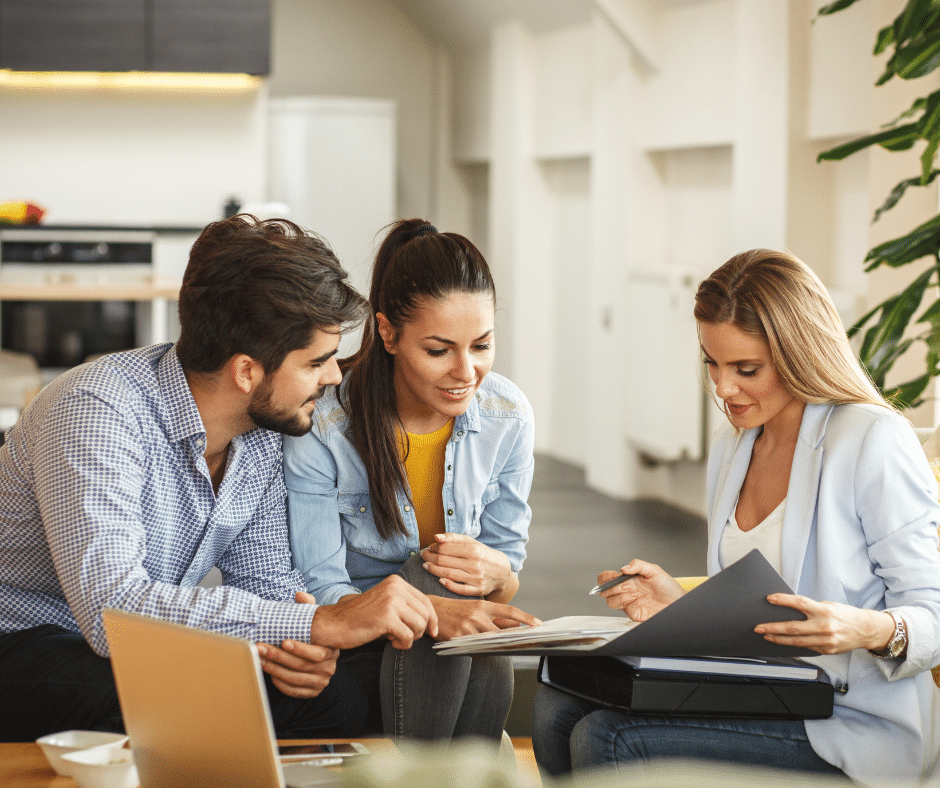 1614018661_cJGkQHbugEys8km7QMu2FECzBWQtGDr0NqUSYXXJ Three people review documents together in a modern office setting, collaborating on a business project. | Sky Rye Design Three people review documents together in a modern office setting, collaborating on a business project.