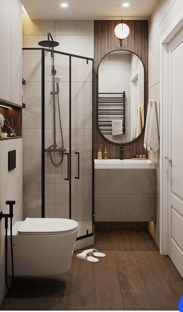 Modern bathroom with glass shower, oval mirror, and wood accents. Cozy and elegant design.