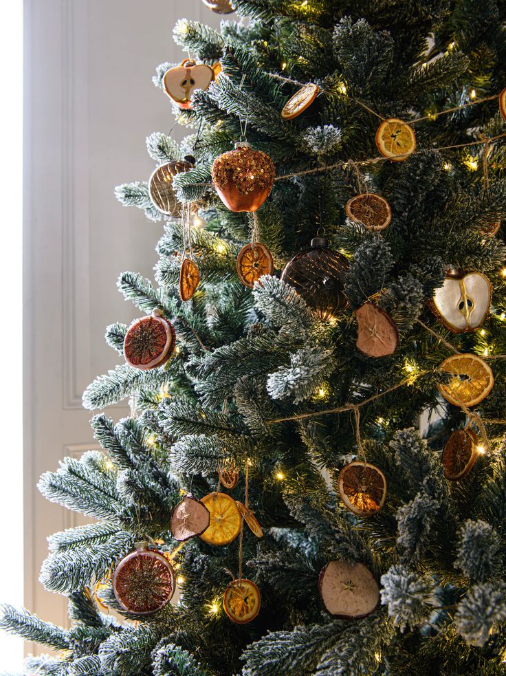 Christmas tree with rustic dried fruit ornaments and warm lights in a cozy holiday setting.