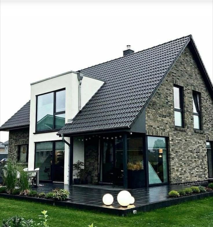 Modern brick and glass house with sloped roof and landscaped garden, showcasing contemporary architectural design.