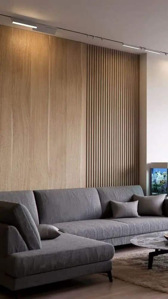 Modern living room with grey sectional sofa, wood panel wall, and soft lighting for a cozy, stylish ambiance.
