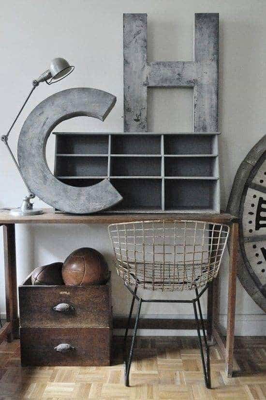 Vintage desk setup with large metal letters, wire chair, old lamp, and box with basketballs. Retro industrial style.