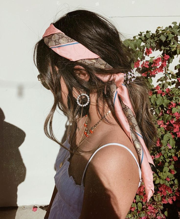 _ 19 Woman with a pink headscarf and jewelry stands by flowering plants on a sunny day. | Sky Rye Design Woman with a pink headscarf and jewelry stands by flowering plants on a sunny day.