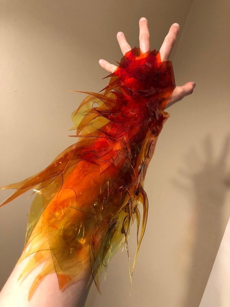 Hand with vibrant orange and red fiery plastic arm sleeve, lit against a neutral background.