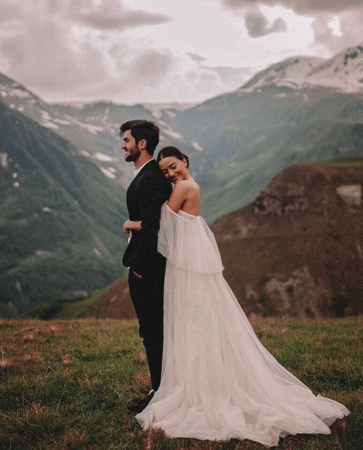Bride and groom embrace in a scenic mountain landscape, capturing a romantic wedding moment in nature.
