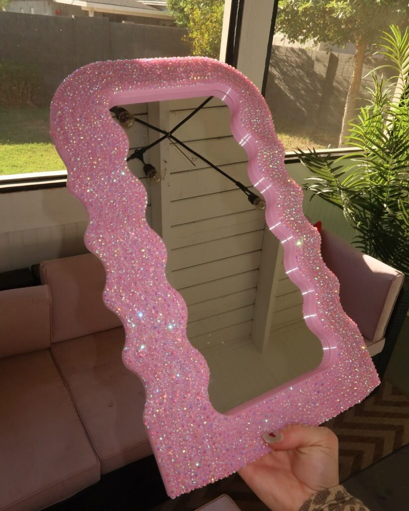 Glamorous pink wavy mirror with sparkling texture, perfect for stylish home decor and modern interior accents.