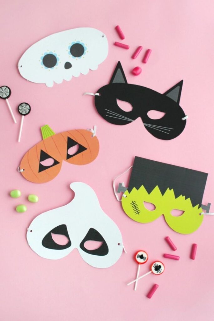 196737f01d9108d0b3f7dd30e33236e8 Halloween masks with cat, pumpkin, and ghost designs on pink background, surrounded by candies and lollipops. | Sky Rye Design Halloween masks with cat, pumpkin, and ghost designs on pink background, surrounded by candies and lollipops.
