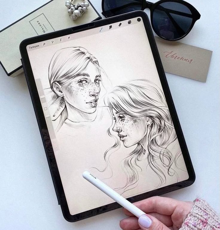 19f04ac7-e8ba-4efd-a6ec-be1472cc5b72 Digital sketch of two freckled faces on tablet with stylus and sunglasses nearby. | Sky Rye Design Digital sketch of two freckled faces on tablet with stylus and sunglasses nearby.