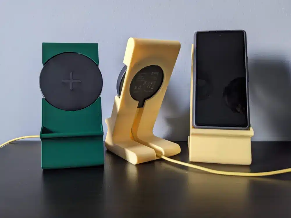 Three wireless chargers with stands, two in green and yellow, one charging a smartphone on a dark surface.