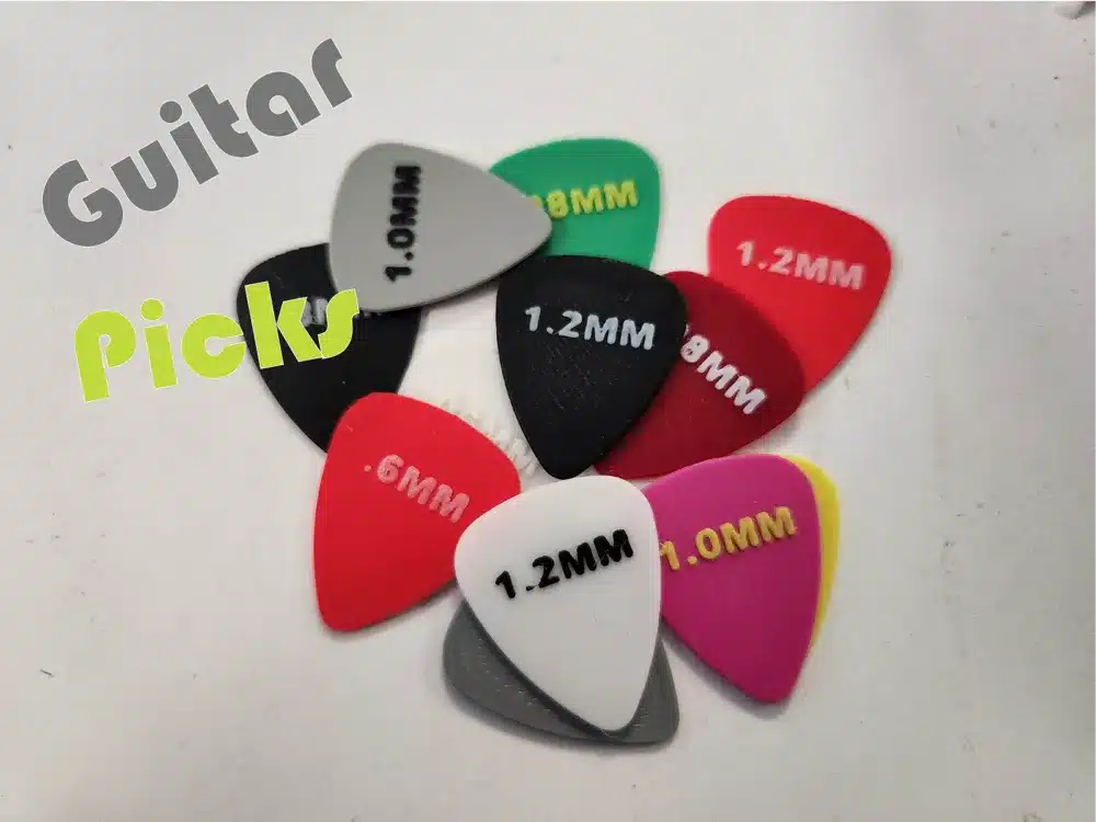 Colorful guitar picks in various thicknesses arranged on a surface, showcasing options for musicians.