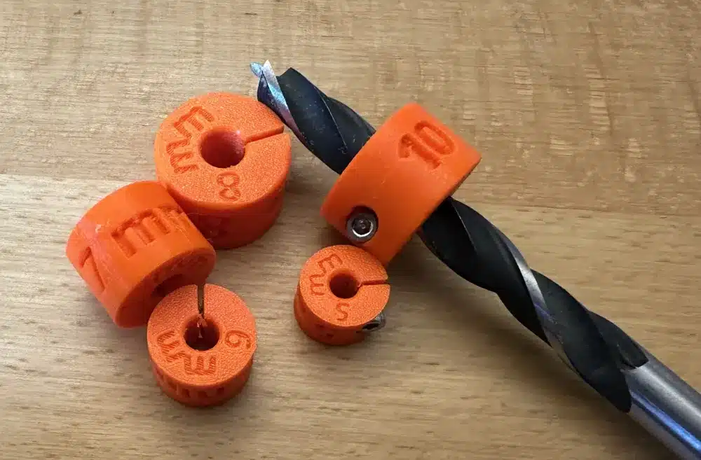 Orange drill bit depth stops on a wooden surface, used for precise drilling measurements.
