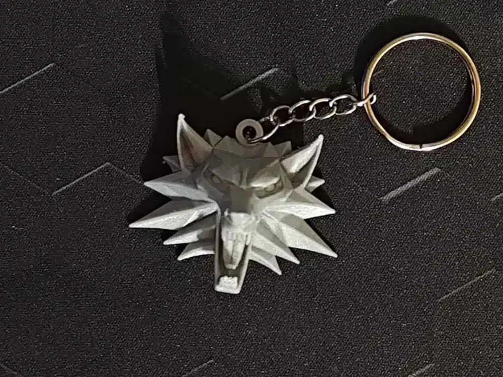 Silver wolf medallion keychain on dark textured background, featuring a fierce, open-mouthed design.