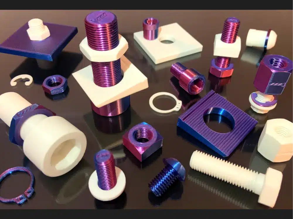 Assorted colorful mechanical components on a reflective surface, featuring bolts, nuts, and washers.