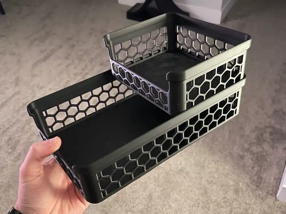 Black hexagonal plastic organizer with two tiers, held by a hand, ideal for storage and organization.
