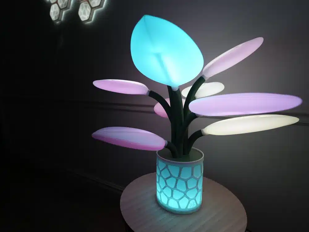 Colorful LED plant lamp with geometric base on a table, illuminating a room with vibrant, futuristic lighting.