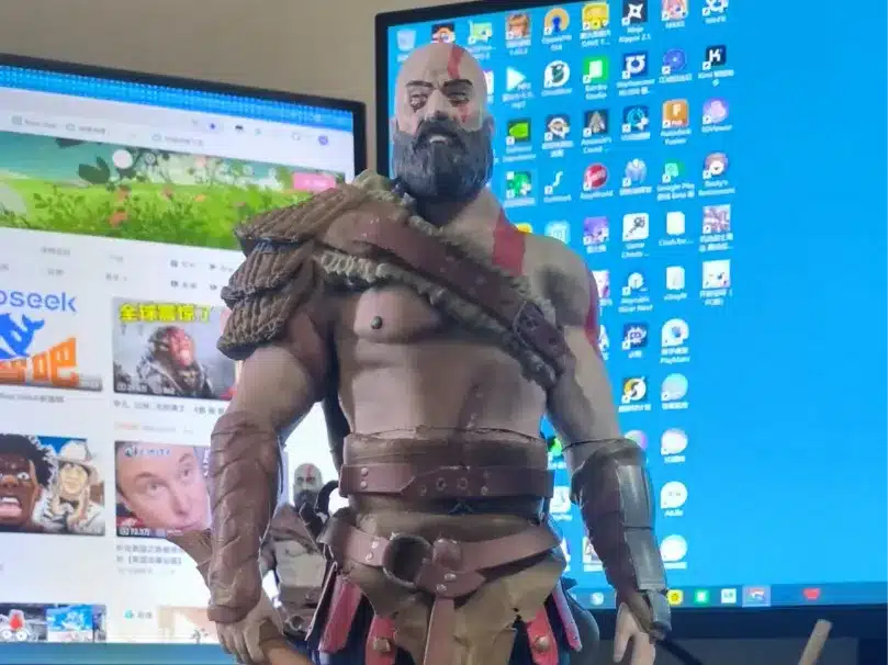 A detailed figurine of a warrior with computer monitors in the background displaying various software icons.