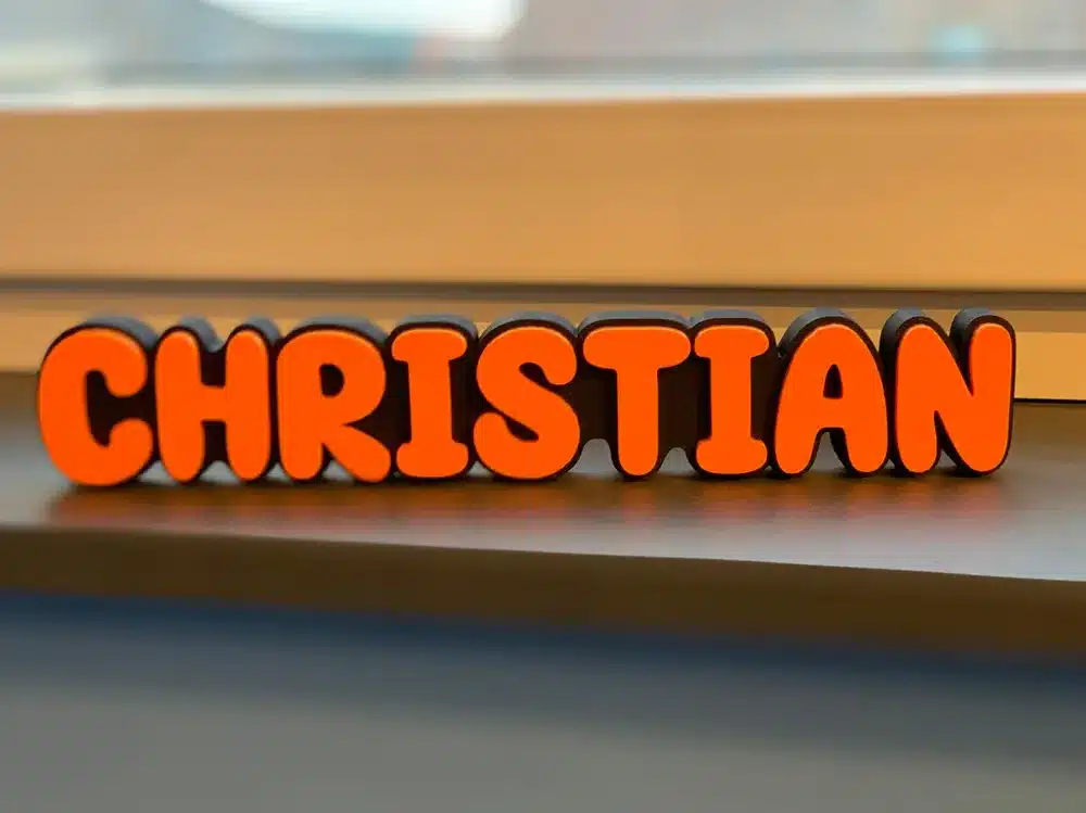 Bold orange letters spelling Christian on a windowsill, creating a vibrant and playful display.