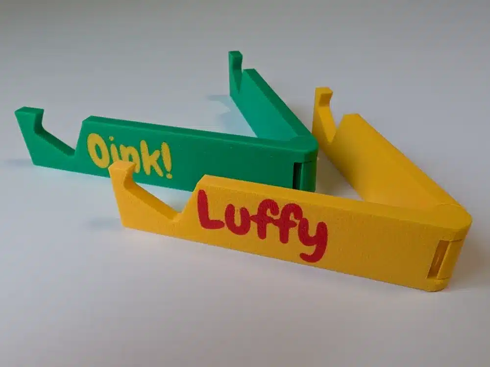 Colorful 3D-printed door openers with playful text Oink! and Luffy on a white background.