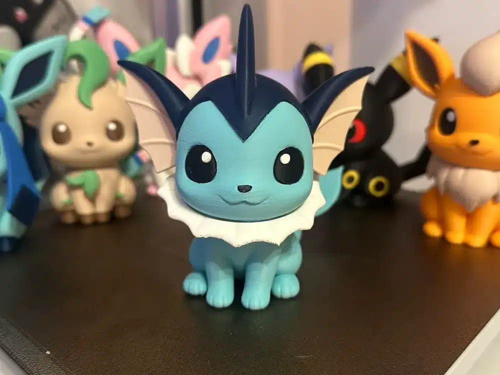 Cute blue aquatic creature figurine with others in the background, displayed on a shelf.