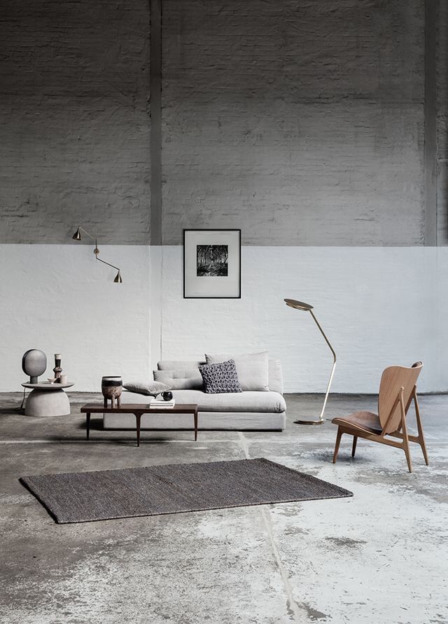 Minimalist living room design with a gray sofa, modern chair, and sleek lighting fixtures.