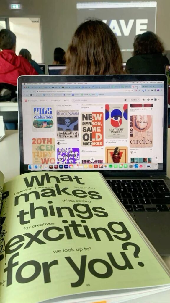 Open book and laptop with design inspirations in a classroom setting. Creative brainstorming environment.