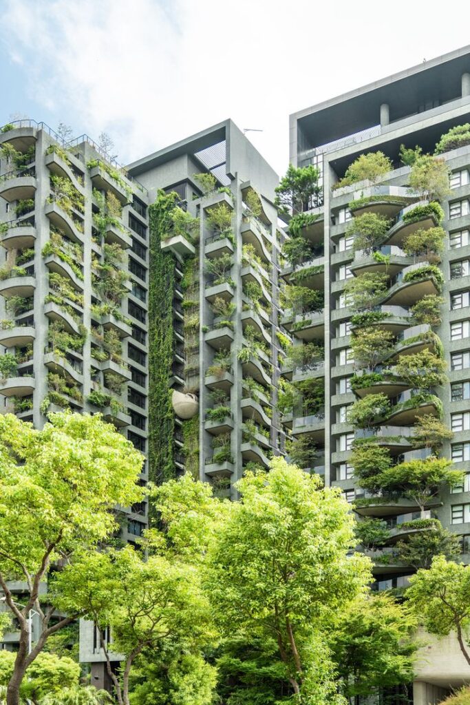 Green building with lush, vertical gardens and trees. Urban eco-architecture showcasing sustainable living design.