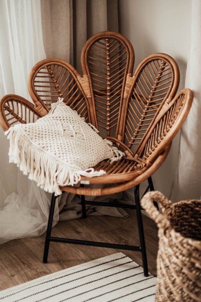 Bohemian rattan chair with a textured pillow in a cozy living room corner, next to beige curtains and a striped rug.