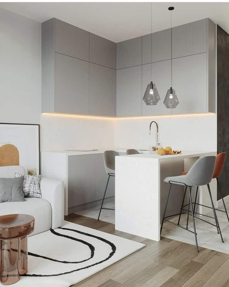 Modern kitchen with sleek gray cabinets, island with bar stools, contemporary lighting, and cozy living area.