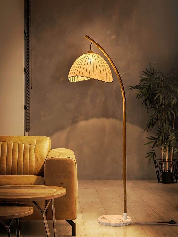 Stylish floor lamp with a curved design next to a leather sofa in a cozy living room setting.