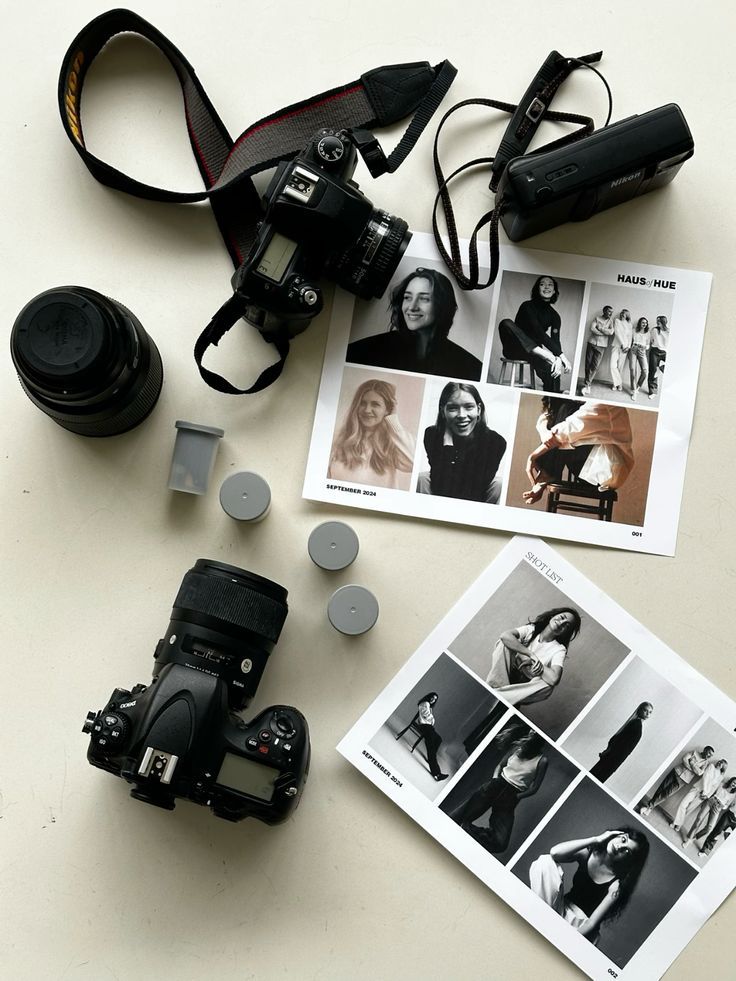 Photography gear and fashion photo prints on a table, showcasing camera equipment and model images for a shoot.