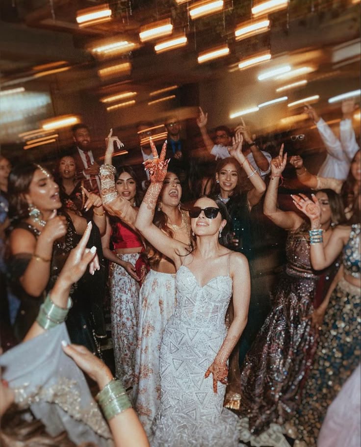 A lively wedding dance floor with joyful guests celebrating in colorful attire and henna designs.
